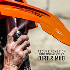 Person using a spray can on an orange motorcycle with text about reducing dirt and mud adhesion.