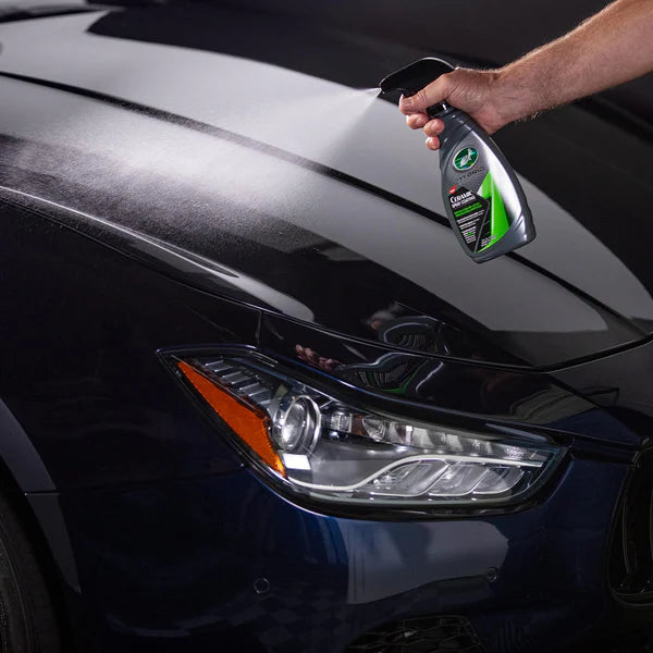 Person cleaning a car's headlight with a spray bottle.