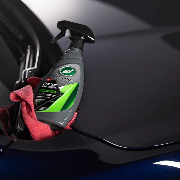 Car care product with a spray nozzle and red cloth on a car surface
