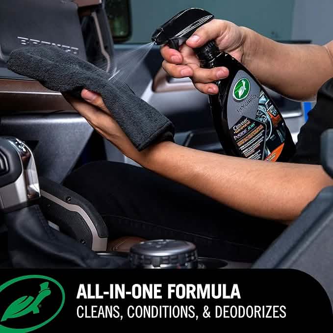 Person cleaning car interior with a spray bottle and towel, with a focus on an all-in-one cleaning formula.