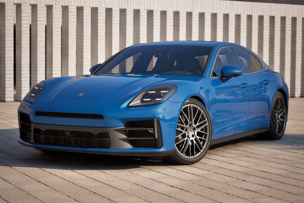 Blue Porsche car parked on a wooden deck with a white wall background